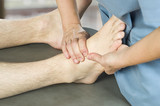 Physiotherapist, chiropractor doing a feet massage to man patient. Osteopathy