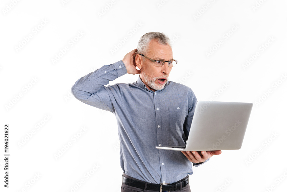 Shocked man in eyeglasses using laptop computer isolated Shocked man in eyeglasses using laptop computer isolated