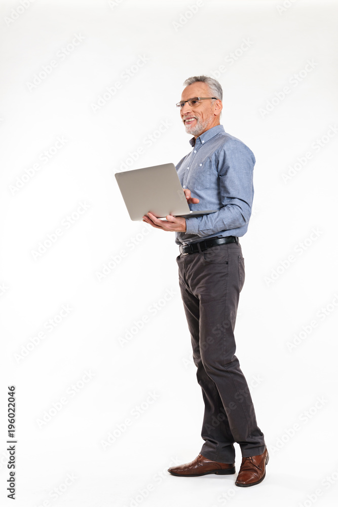 Smiling old man using laptop computer and looking away isolated Smiling old man using laptop computer and looking away isolated