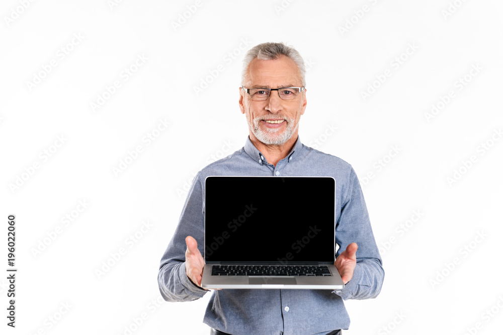 Old smiling man showing laptop with blank screen isolated Old smiling man showing laptop with blank screen isolated