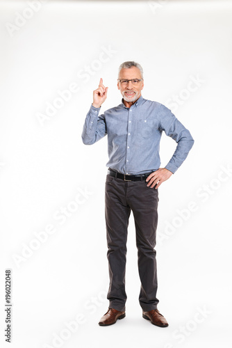 Smiling old man having an idea and pointing up isolated photo