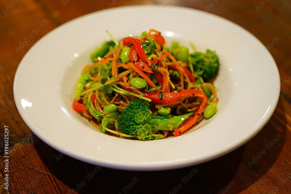 Plate of vegetable soba noodle stir fry with peppers, broccoli and edamame