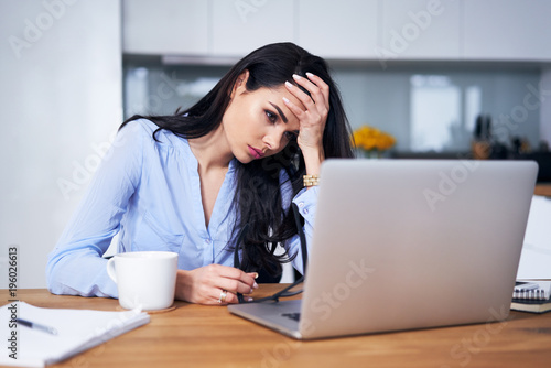 Tired woman working with laptop in home office