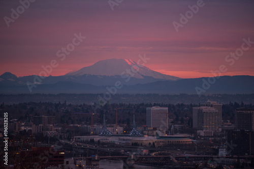 Snowy volcano over city at sunrise