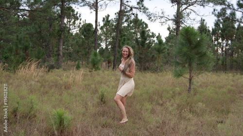 beautiful young blonde woman having fun, smiling, laughing and dancing in a field