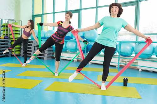 Women doing gym exercises using latex fitness bands