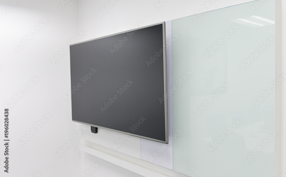 Fototapeta premium LED TV installed to the white wall of the meeting room with white board