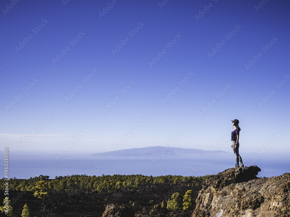 Woman on top of a cliff looking afar in Nature
