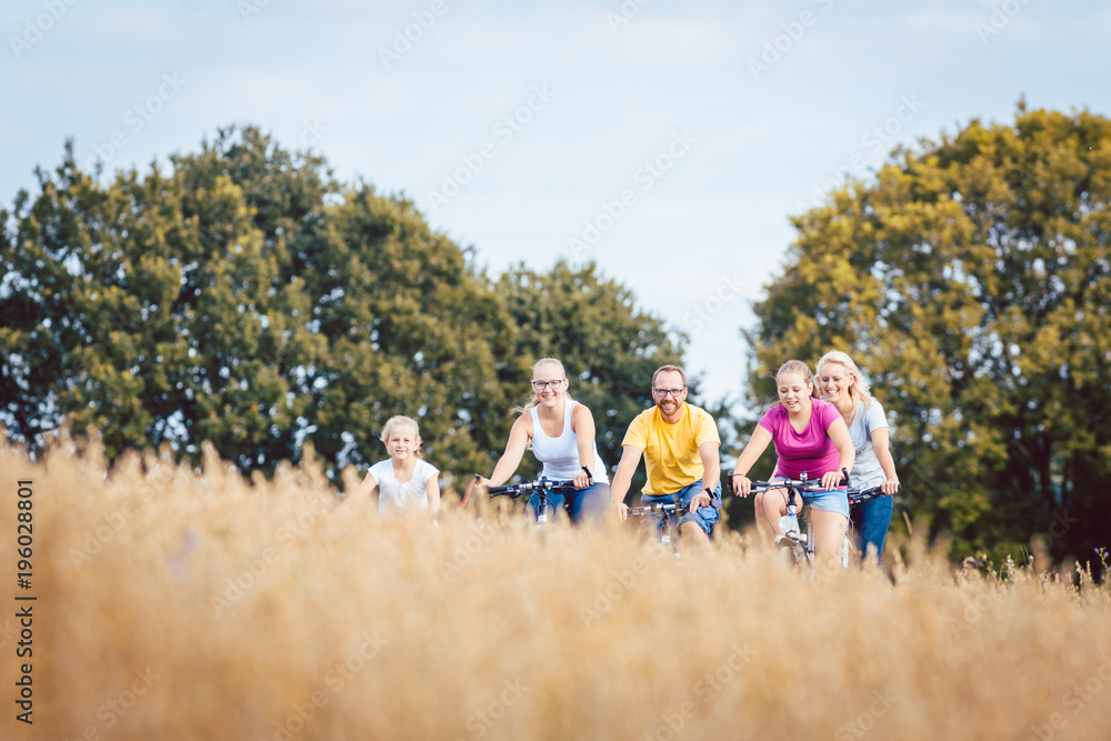 Family riding their bikes shot above a grain field in summer