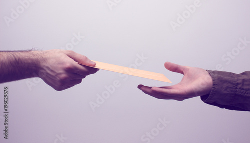 Two men hands receiveng and giving mail in envelope on the white background. Mailtime concept. Close up and toned