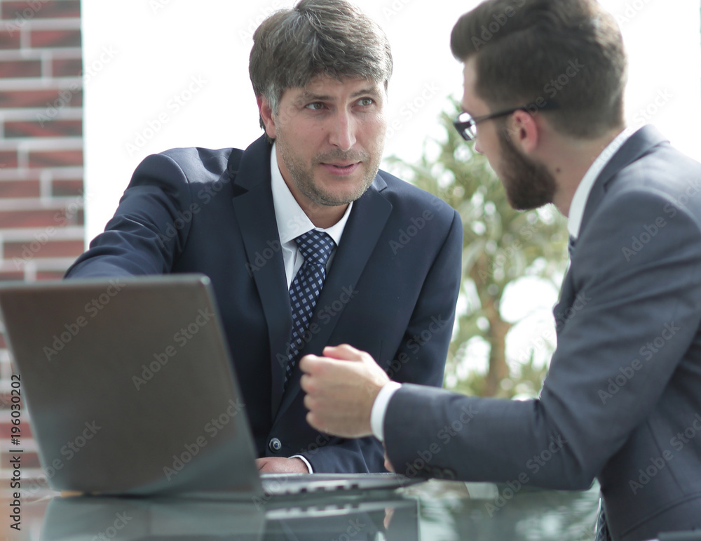 Two businessmen working together using laptop on business meeting in office Two businessmen working together using laptop on business meeting in office