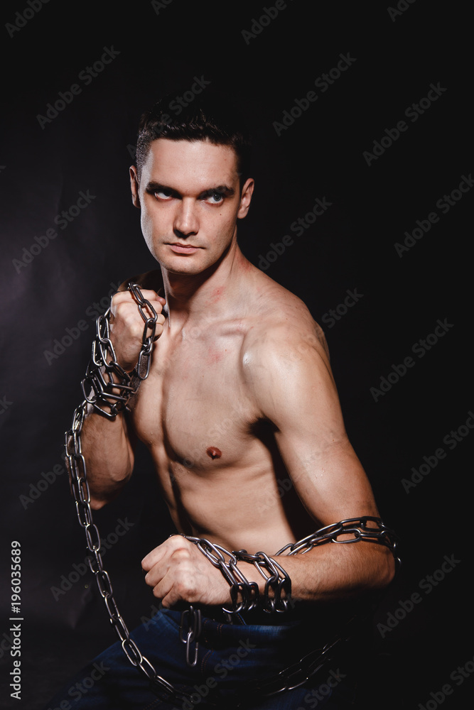 strong, athletic man on a black background with chains