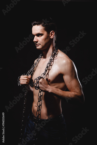 strong, athletic man on a black background with chains