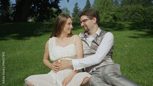 CLOSE UP: Young couple lovingly gaze at each other caressing her pregnant belly