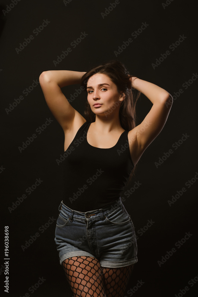 Model test with amazing brunette model in black shirt and jeans shorts posing in the shadows Model test with amazing brunette model in black shirt and jeans shorts posing in the shadows