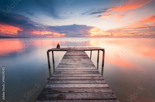 wooden jetty toward horizon during sunset with reflection.