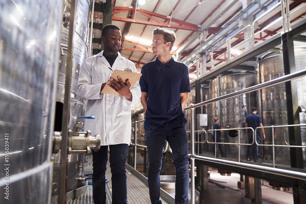 Two male staff members make an inspection at a wine factory