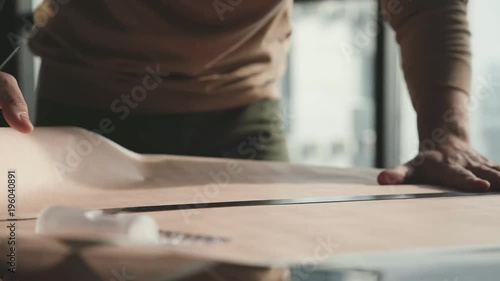 Architect's desk: drawings, tape measure, ruler and other drawing tools. Engineer works with drawings in a bright office, close-up. Insturments and office for designer. Male hands draw with a pencil. photo