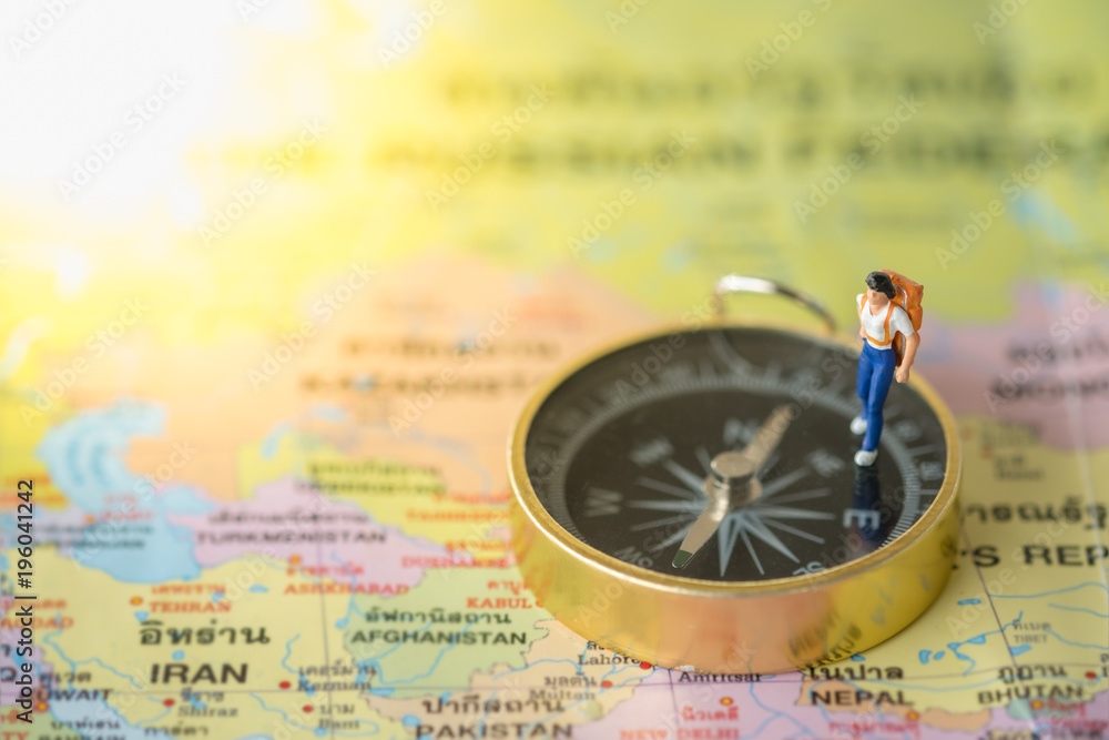 Travel Concept. Traveler miniature figure with backpack walking on compass on world map. Travel Concept. Traveler miniature figure with backpack walking on compass on world map.