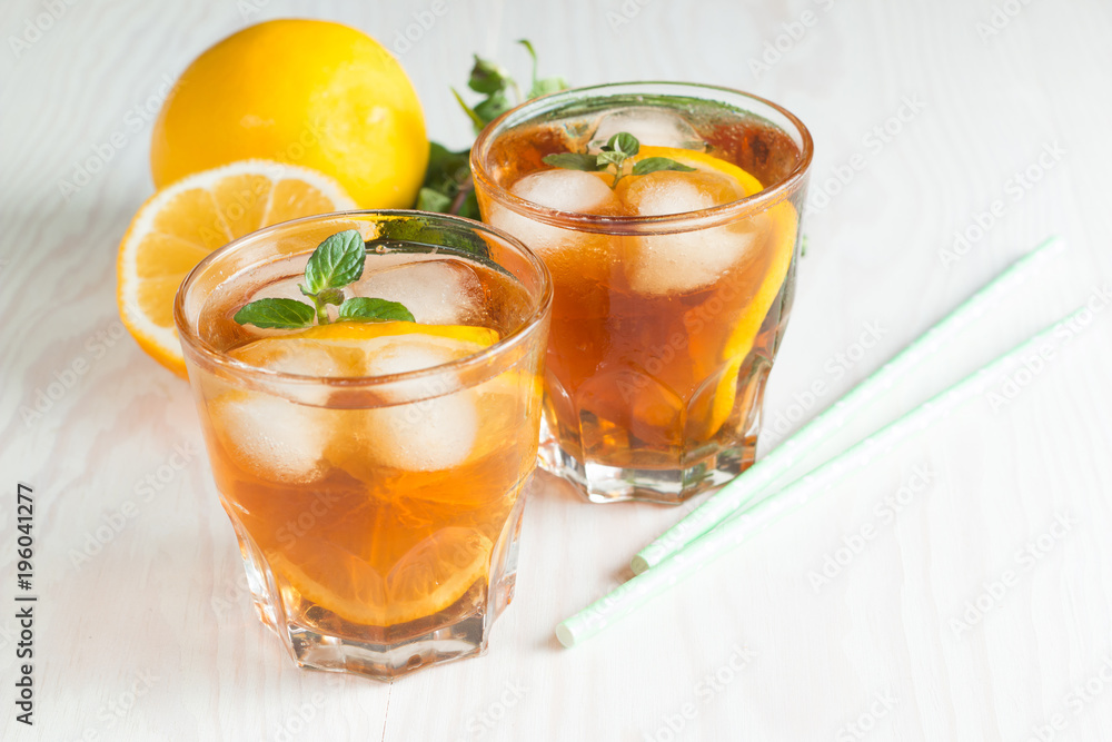 Refreshing citrus lemonade, summer drink. Ice tea with fresh lemon and mint on wooden background. Refreshment beverage concept.