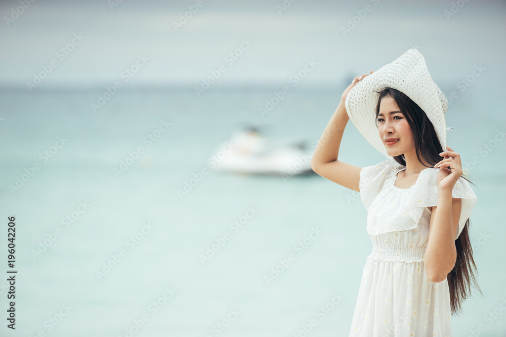 Asian girl wearing a long white dress walking or standing at the beach on vacation weekend. Single lady sitting at the beach by alone. Girl with white dress on the beach. Asian girl wearing a long white dress walking or standing at the beach on vacation weekend. Single lady sitting at the beach by alone. Girl with white dress on the beach.