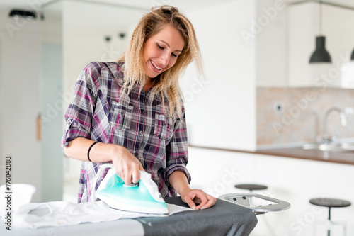 Young Smiling Woman Ironing Clothes On Ironing Board