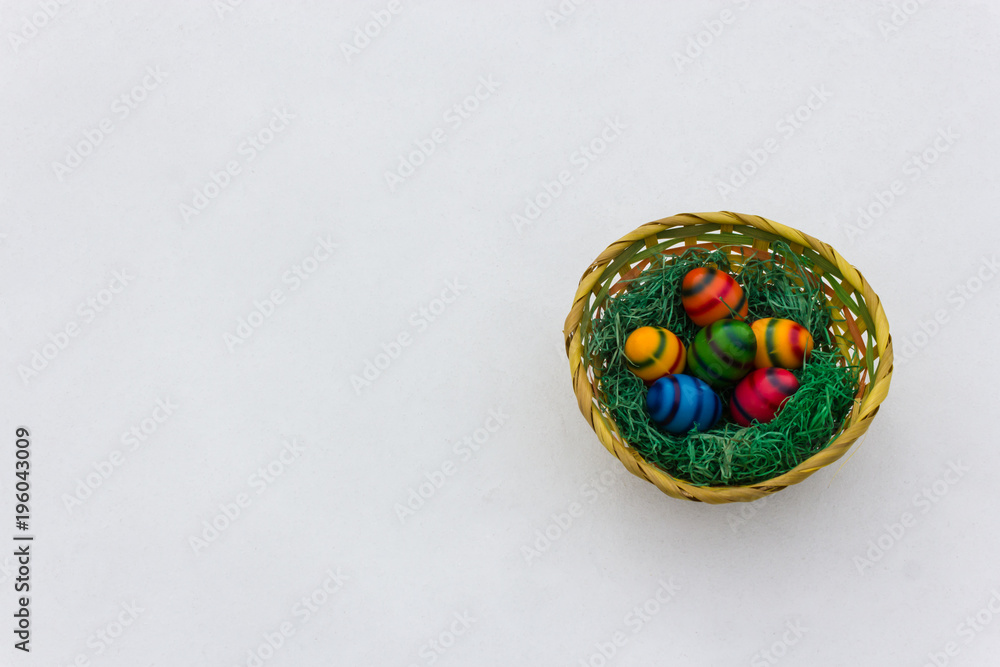 a basket with colored eggs in the snow, easter