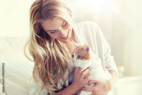 happy young woman with cat in bed at home