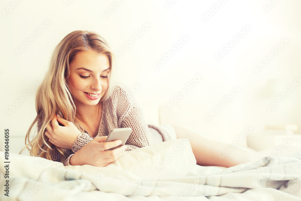 happy young woman with smartphone in bed at home happy young woman with smartphone in bed at home