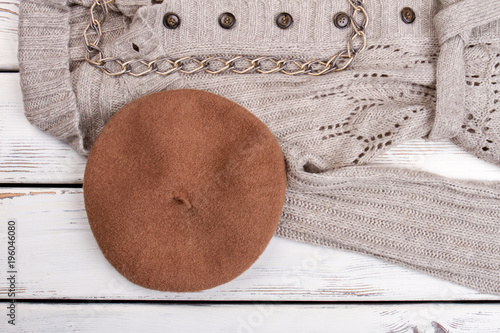 Brown berete hat on grey woolen coat. Bright wooden desk background. photo