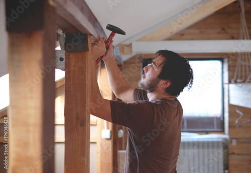 Man building a house and workimg with hammer and wood photo