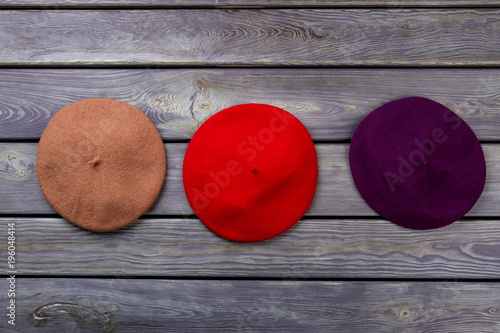 Berete hats on wooden background. Brown, red and purple hats. photo