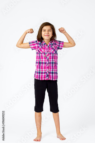 Young Girl Flexes With a Proud Smile on a White Background