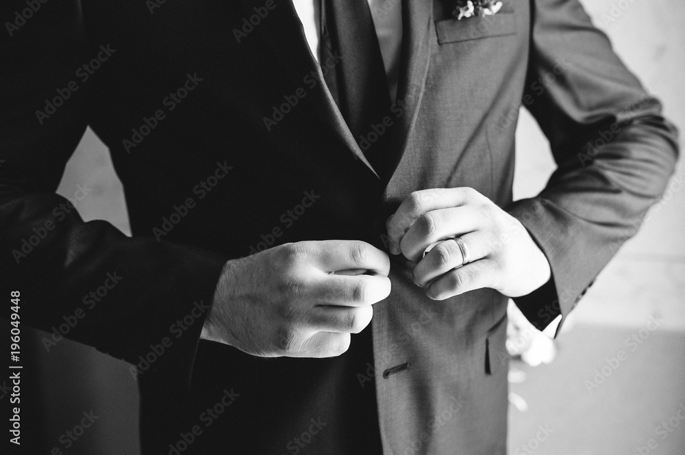 the groom is putting on his wedding suit, black and white photo