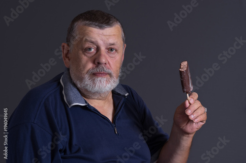 Nice portrait of a bearded senior with nibbled ice-cream on a stick