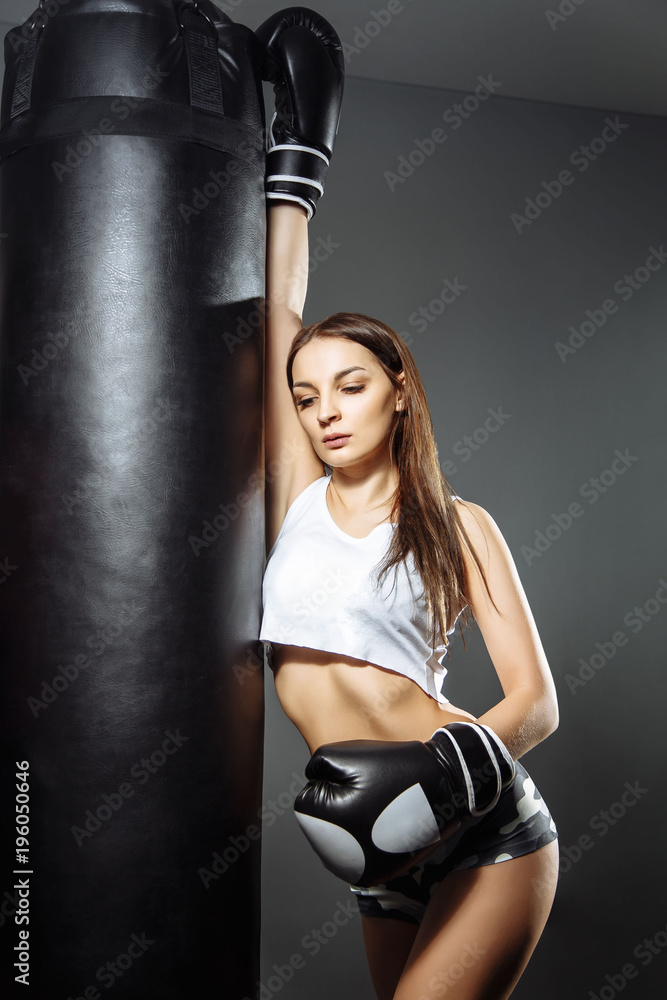 Portrait of a young beautiful woman with boxing gloves in the gym