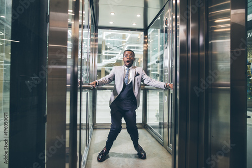 african Businessman screaming in the elevator. fear claustrophobia concept