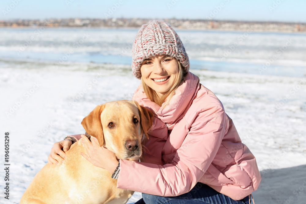 Portrait of woman hugging cute dog outdoors on winter day. Friendship between pet and owner
