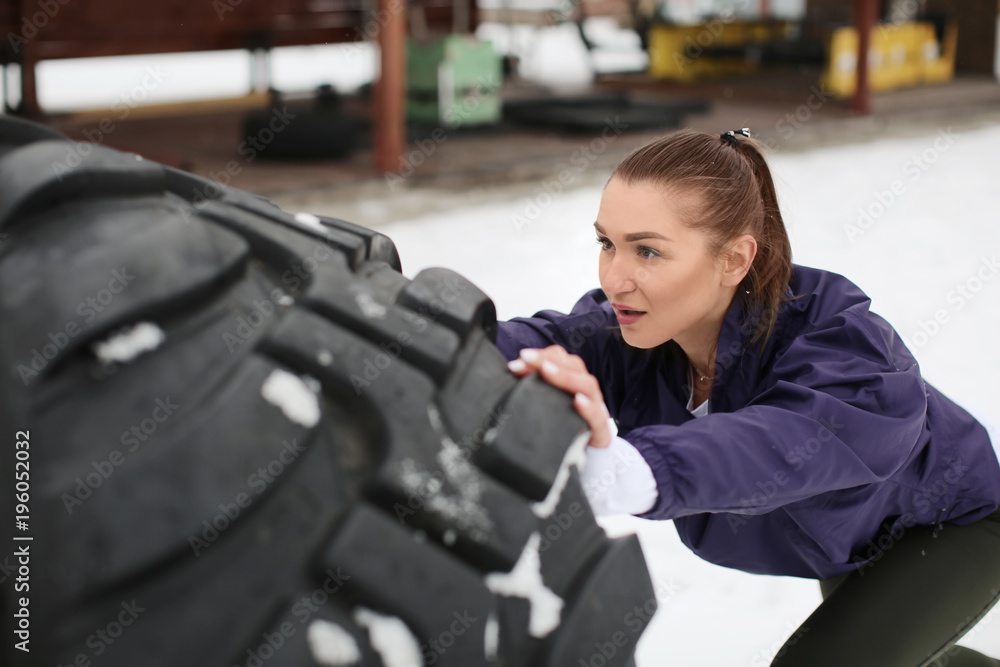 Young sporty woman flipping heavy tire, outdoors Young sporty woman flipping heavy tire, outdoors