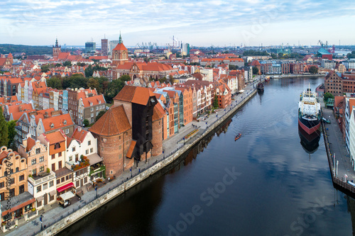 Gdansk old city in Poland with the oldest medieval port crane (Zuraw) in Europe, St John church, Motlawa River, old granaries, ships and boat. Aerial view in early morning. 