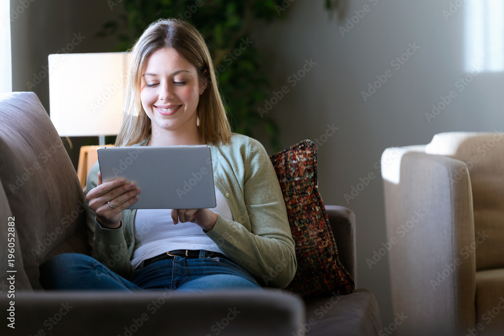 Beautiful young woman using her digital tablet at home. Beautiful young woman using her digital tablet at home.