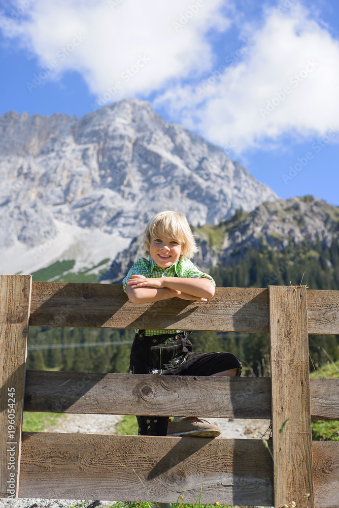 Smilling Bavarian boy in a beautiful mountain landscape.Happy little boy wearing a traditional Bavarian clothes