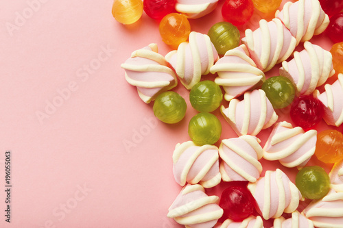 Border of marshmallows and colourful sweets on pink background