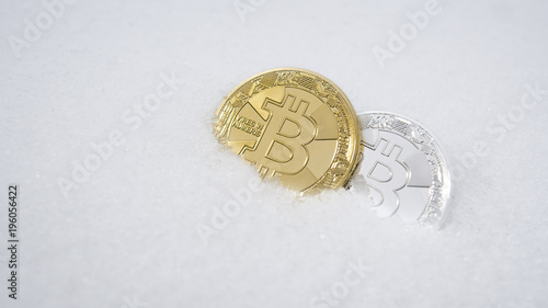 Gold and silver bitcoin. Cryptocurrency on snow, in the background. The concept of freelancing, the stock exchange. Gold bitcoin on cold winter snow background. Frozen bitcoin. Frozen account.