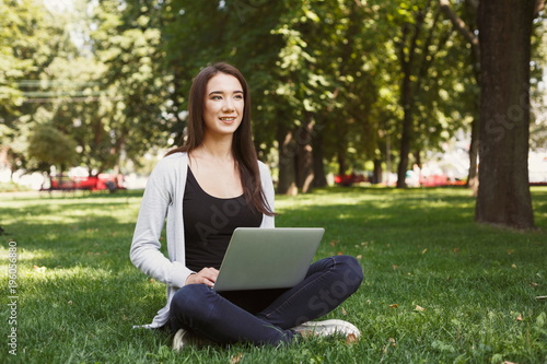 Young pensive woman using laptop in park