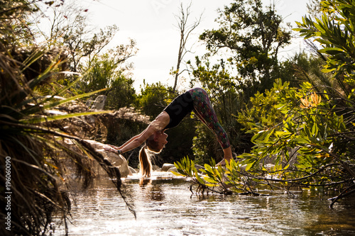 female performing yoga pose with scenic mountain and river background