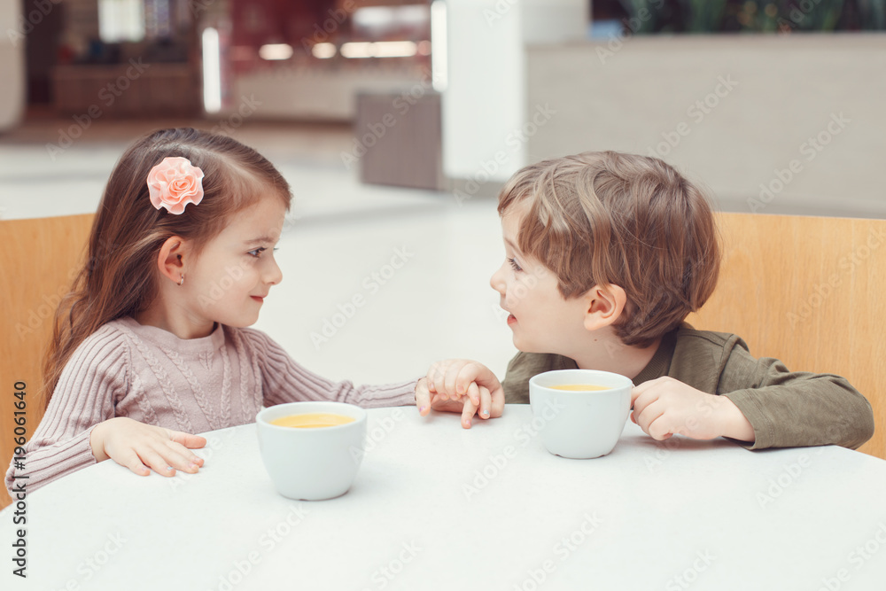 Group portrait of two white Caucasian cute adorable funny children toddlers sitting together drinking juice. Love friendship childhood concept. Best friends forever. Kids holding hands Group portrait of two white Caucasian cute adorable funny children toddlers sitting together drinking juice. Love friendship childhood concept. Best friends forever. Kids holding hands