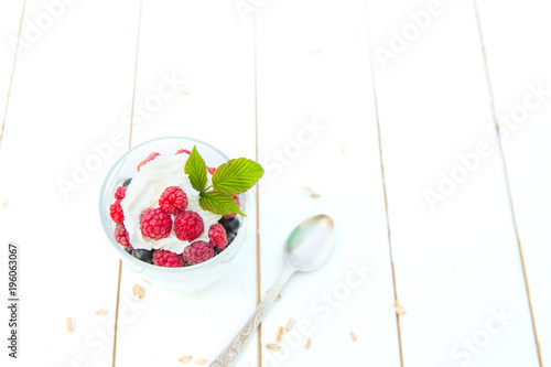 Layered dessert with raspberry cream cheese in glass on white wooden table. View from above photo