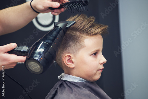 Obraz na płótnie Hairdresser making a hairstyle to a boy in barbershop. w salonie