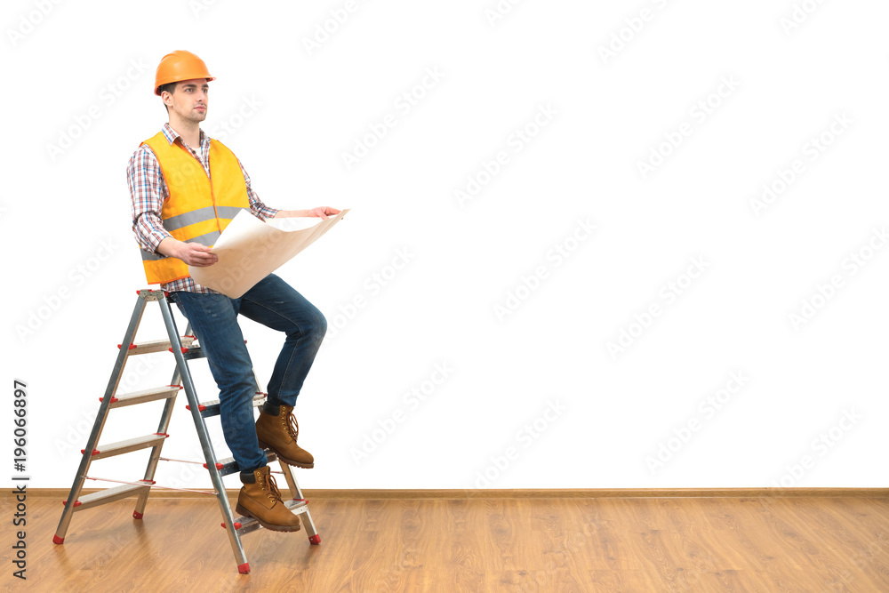 The engineer with a paper standing on the ladder on the white wall background The engineer with a paper standing on the ladder on the white wall background